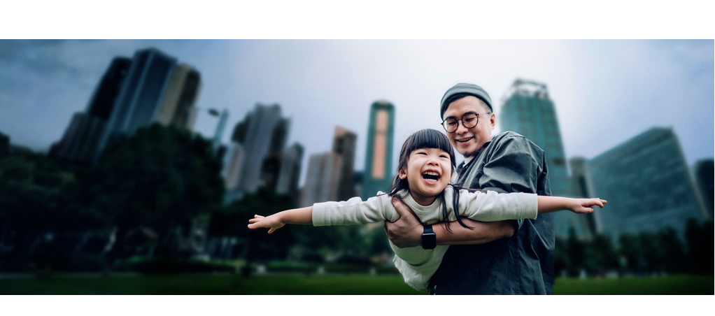 Happy little Asian girl having fun with her father outdoors in urban park. She is pretending to be an airplane, flying up in the sky while her father lifting her into the air. Family love and lifestyle
